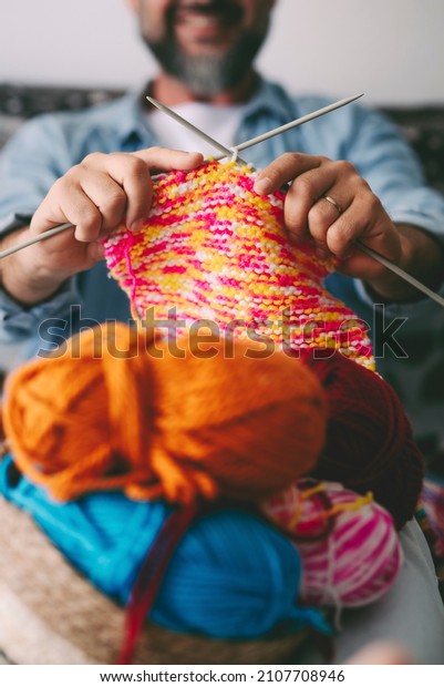 Close up of adult man\
working with ball yarn of colorful wool. Happy people in indor\
hobbies activity using woolen and doing knitting work. Indoor\
leisure activity