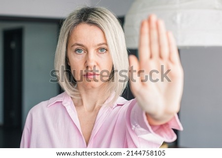 Close up of adult woman show stop gesture sign by hand saying no to domestic violence or abuse, determined middle-aged female protest against abortion or discrimination, nonverbal language concept
