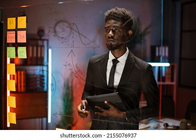 Close Up Of African American Businessman, Working On Project Plan Using Sticky Papers On Glass Wall, Scrum Board. Confident Executive Manager, Holding Digital Tablet