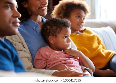 Close Up Of African American Children Sitting On The Sofa In Their Living Room Watching TV With Their Parents, Side View