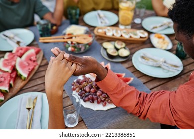 Close up of African American family saying grace at table outdoors and holding hands during gathering - Powered by Shutterstock