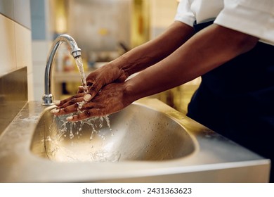 Close up of African American female cook washing hands while working in restaurant kitchen. - Powered by Shutterstock