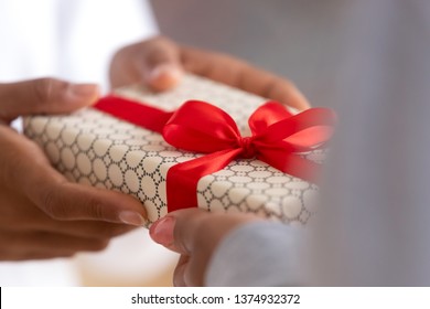 Close up African American female hands holding gift box, teenage girl congratulating mother with mothers day or birthday, black mom receiving present from daughter, holiday celebration concept - Powered by Shutterstock