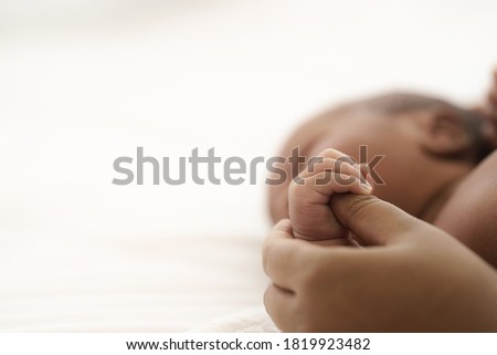 Close up of african american infant baby hand holding mother thumb