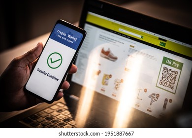 Close up of an African American male hand holding mobile phone with QR pay application on the screen, laptop in the background