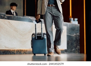 Close up of African American man with luggage and passport in hotel hallway. Copy space.