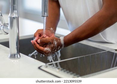 Close up of an African American man washing his hands in the sink.￼￼ - Shutterstock ID 2213095539