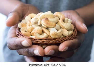 Close Up African American Woman Dark Brown Skin Hands Holding A Basket With Cashew Nuts. Healthy Food And Snack For Healthy Eating And Oils Concept