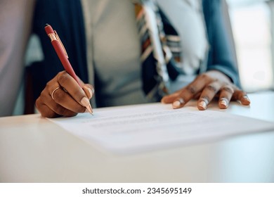 Close up of African American woman signing insurance agreement in the office.  - Powered by Shutterstock