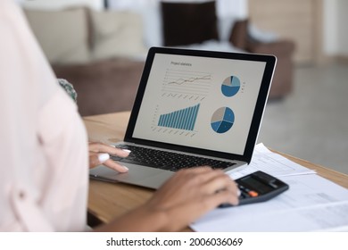 Close up African American woman working financial project with statistics, using laptop and calculator, preparing presentation for report, calculating bills or investments, planning managing budget
