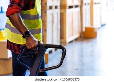 Close up of african black warehouse worker hand hold hand pallet jack in distribution warehouse with copyspace. Business warehouse and logistic concept.