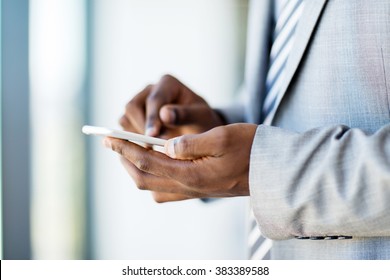 Close Up Of African Businessman Hands Texting On Smart Phone