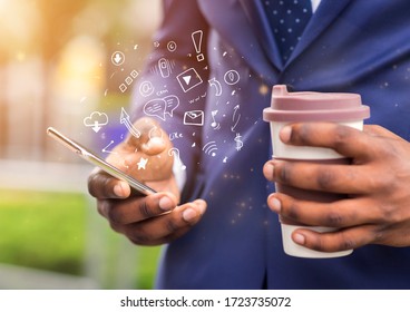 Close up of african businessman holding coffee to go and using brand new mobile phone with functional icons