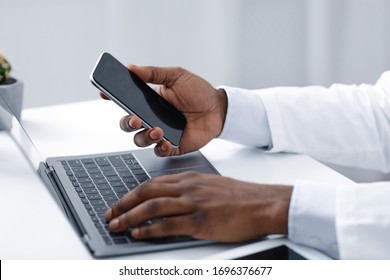 Close Up Of African Doctor Hands Holding Phone And Using Laptop