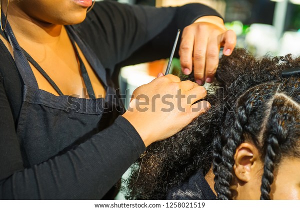 Close\
up african hairstylist braided hair of afro american female client\
in the barber salon. Black healthy hair culture and Style. Stylish\
therapy professional care concept. Selective\
focus