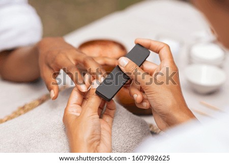 Close up of african hands of a qualified manicurist filing the nails of a young woman. Hands during manicure care session. Detail of a girl in a nail salon receiving manicure.