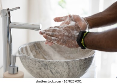 Close Up African Man Cleans Hands With Soap In Bathroom. Anti Bacterial Agent Sanitizer That Contains Alcohol Kill Microbe And Bacteria, Safety Precautions Against COVID-19, Personal Hygiene Concept