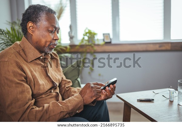 Close up of African man hands checking\
blood sugar level by Glucose meter for diabetes tester using as\
Medicine, glycemia, healthcare and medical\
concept.
