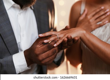 Close up of african man in love putting wedding ring on his woman finger