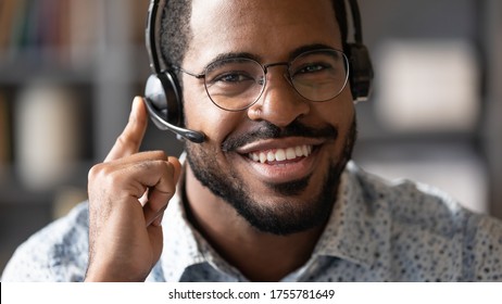 Close up african man wear headset with microphone smile look at camera. Internet selling worker, tutor provide lecture for trainee distantly, company representative contact with client online concept