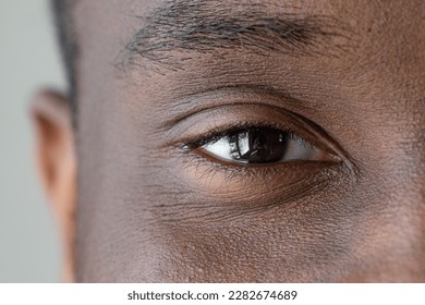 Close up of an African man's face. Eye macro with black iris. Close-up details and visible masculine features. Eyelashes and eyebrows in order. - Powered by Shutterstock