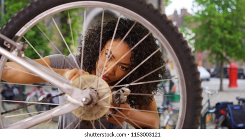 Close up of African woman fixing wheel or tire on bike while in city square - Powered by Shutterstock