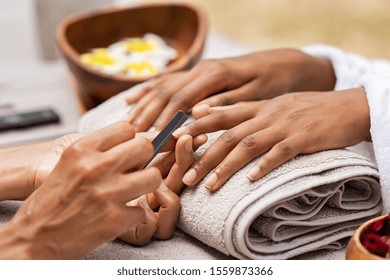 Close Up Of African Woman Hand Getting Manicure In Spa Salon. Detail Of Black Hands Getting Manicure Treatment At Luxury Spa. Girl In A Nail Salon Receiving Treatment By A Beautician With Nail-file.