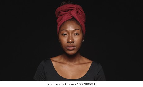 Close up of african woman isolated on black background. African female with a scarf wrapped on head looking at camera. - Powered by Shutterstock