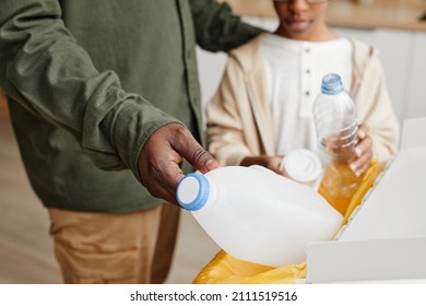 Close up of African-American father and son putting plastic in recycling bins at home, copy space - Powered by Shutterstock