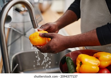 Close up of African-American man washing fresh vegetables while cooking in kitchen, copy space - Powered by Shutterstock