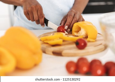 Close up of a afro american woman chopping vegetables to make a salad at the kitchen