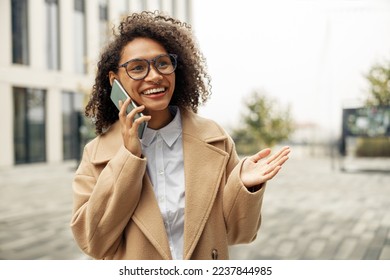 Close up of afro american woman wearing glasses talking phone with friends during city walking - Powered by Shutterstock