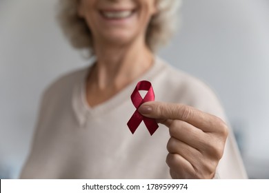 Close up aged female show to camera red ribbon symbol, substance-abuse prevention, solidarity of people living with HIV awareness fight against AIDS. World AIDS Day. Health check up promotion concept