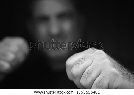Close up of aggressive violent hitting man fists emerging from the darkness.Dangerous bulling male mental health illness rehabilitation concept. Real people. Copy space