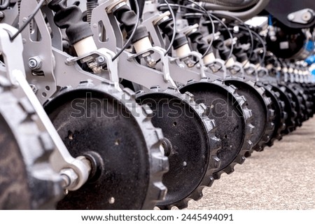 Close up of agricultural machinery, focusing on metal discs aligned in a row, showcasing agricultural equipment parts.