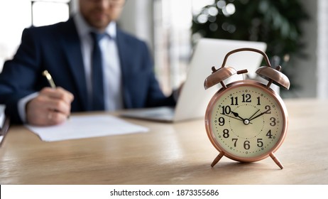 Close Up Alarm Clock On Desk, Businessman Wearing Suit Using Laptop, Working With Correspondence On Background, Entrepreneur Involved In Working Process, Workday, Time Management Concept