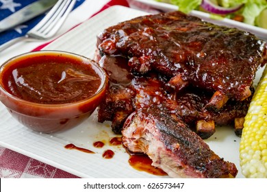 Close Up Of All American Picnic With Bbq Ribs And Whiskey Bourbon Bbq Sauce With Ear Of Corn And Fresh Salad Side Dish