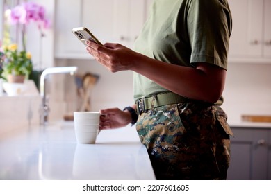 Close Up Of American Female Soldier In Uniform In Kitchen On Home Leave With Mobile Phone