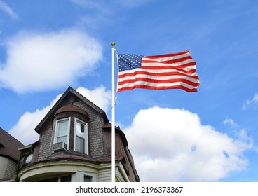 Close Up Of American Flag In Front Of Victorian Style Home In Midwest USA