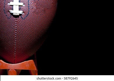 close up of an american football against a black background