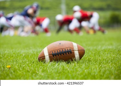 Close Up Of An American Football On The Field, Players In The Background