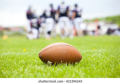 Close Up Of An American Football On The Field, Players In The Background