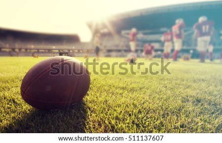 Close up of an american football on the field, players in the background