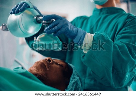 Close up of anesthesiologist using mask on a patient during surgery in operating room.