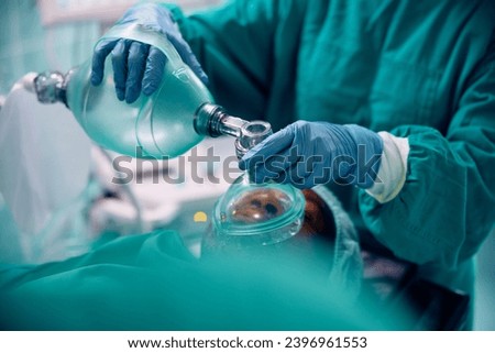 Close up of anesthesiologist using oxygen mask on patient during surgery in the hospital.