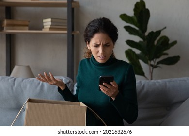 Close up angry woman using phone, looking at screen, unpacking parcel, dissatisfied by broken or wrong online order, unhappy confused customer displeased by post shipping, bad delivery service