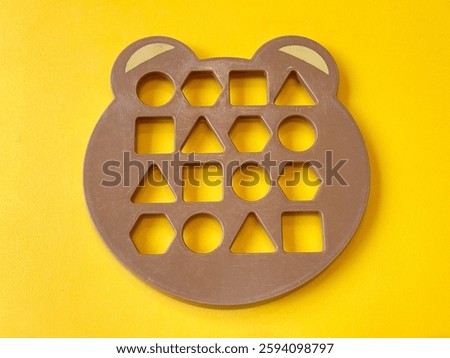Close up of animal bear shape template for kids. Geometrical shape molding for toddler and kids in playground, isolated on yellow background.