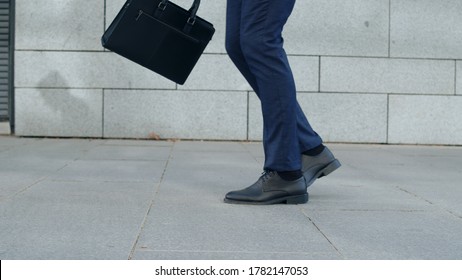 Close Up Anonymous Businessman Feet Dancing On Street Alone. Low View Male Employee Holding Briefcase In Hand Outside Office. Businessman Walking For Work On Road In Slow Motion