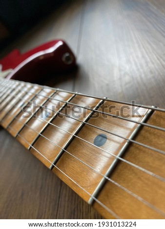 close up apple red scallop electric guitar neck and nickel stings on veneer wood background with copy space for letter in Vertical photo. business and music concept. Wallpaper or background for book.