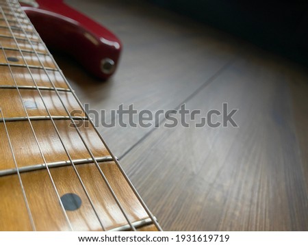 close up apple red scallop electric guitar neck and nickel stings on veneer wood background with copy space for letter. business and music concept. Wallpaper or background for book.